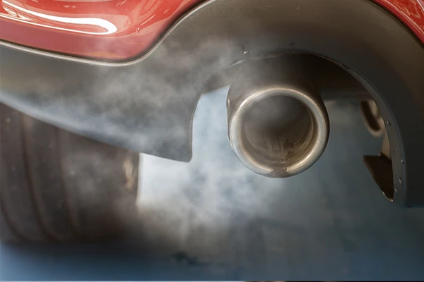 close up view of a vehicles exhaust with smoke remnants coming out of the pipe